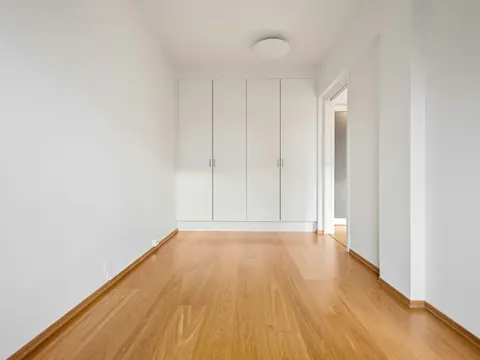 Pièce vide et lumineuse, parquet et murs blancs, prête à emménager